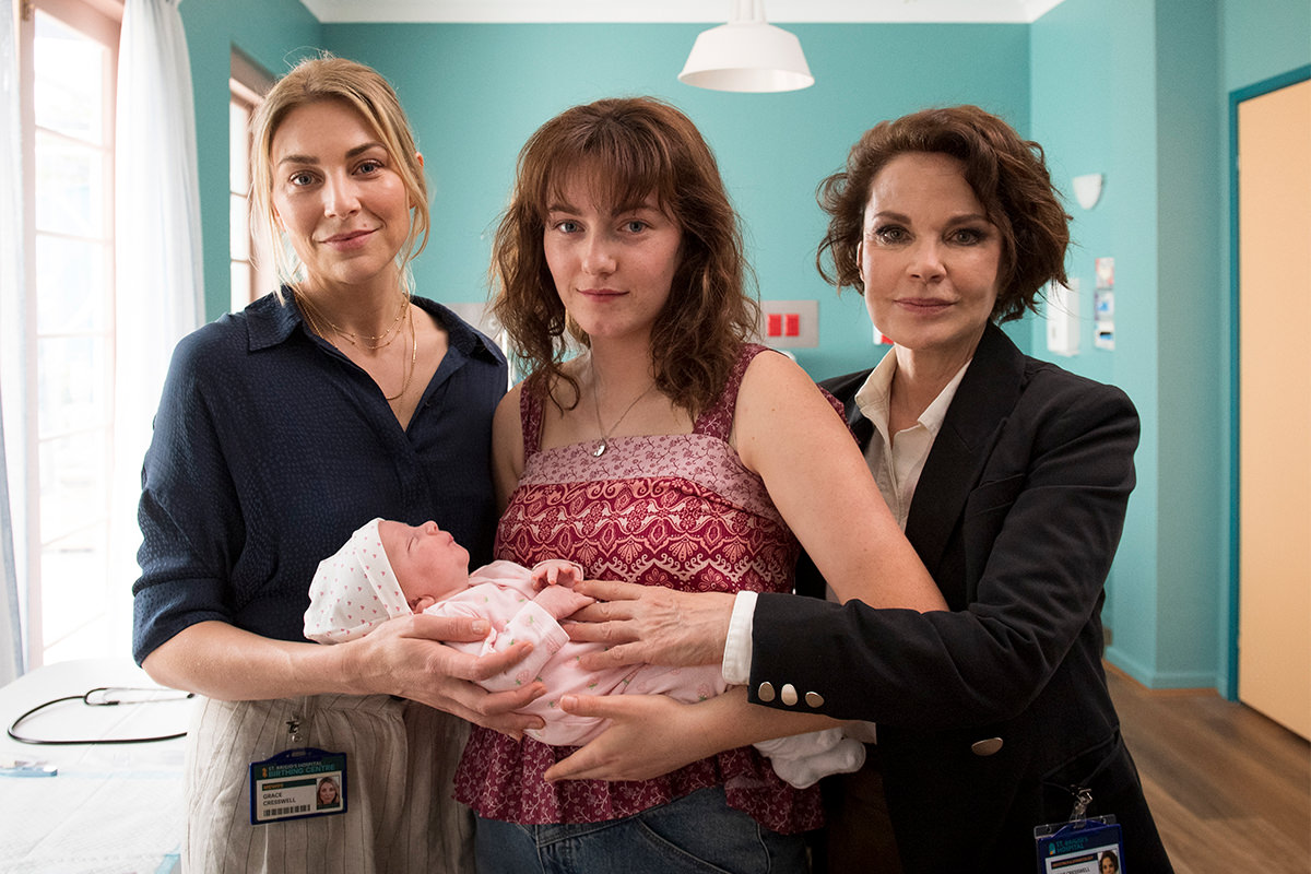 Production still from Amazing Grace, three women hold a newborn baby.