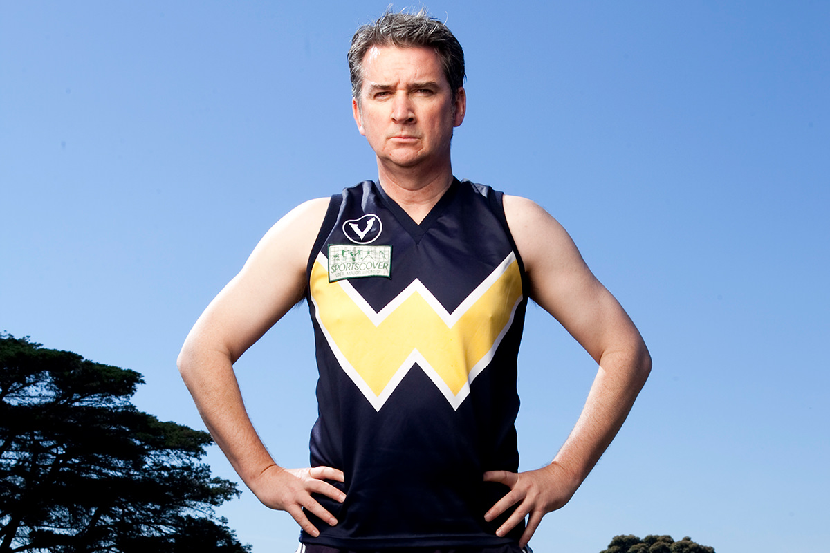 A man wearing an AFL jersey stands with his hands on his hips