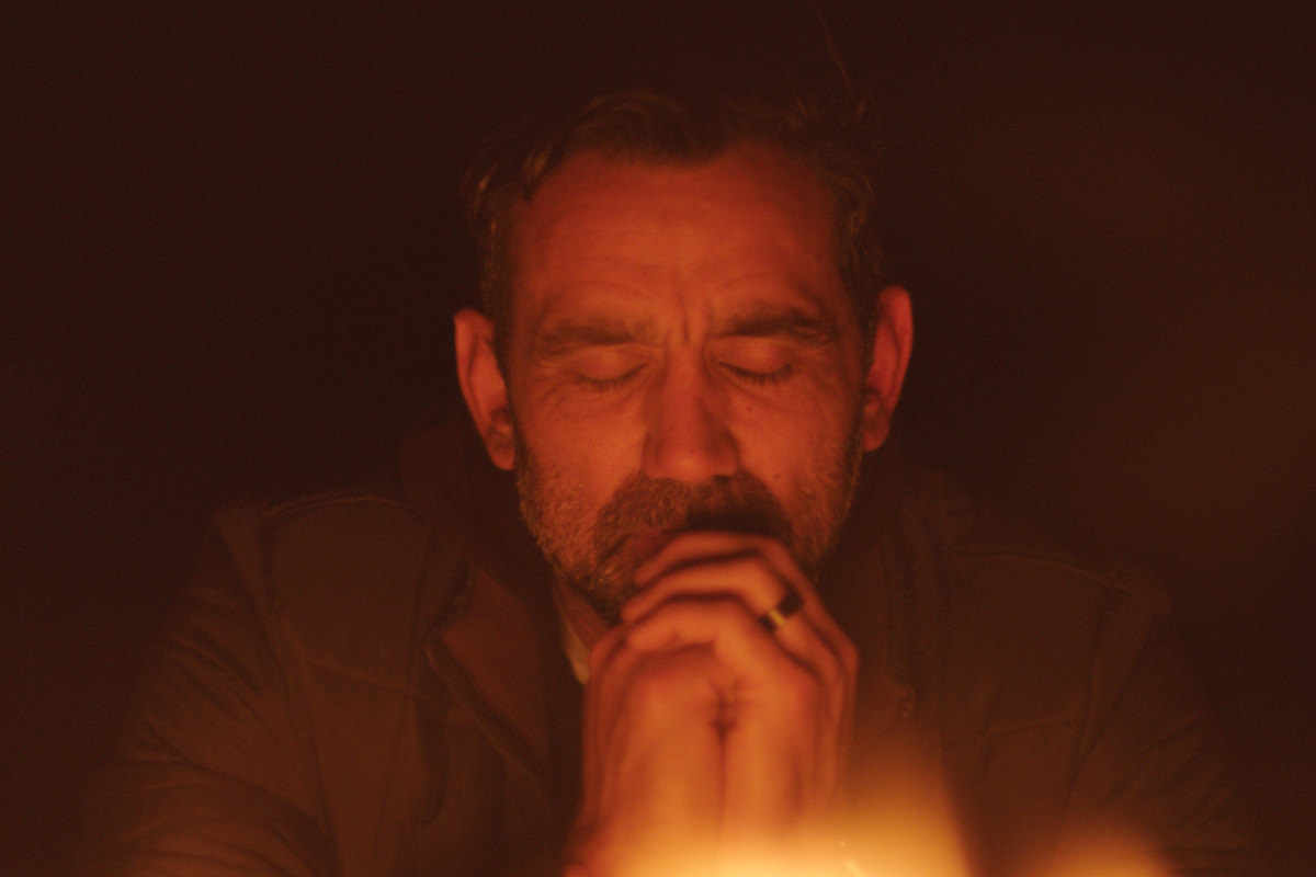 Adam Goodes sits with his eyes closed in front of a fire in documentary The Australian Dream