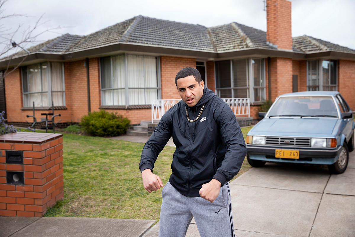 Theo Saidden posing as 'Superwog' out the front of a red brick house