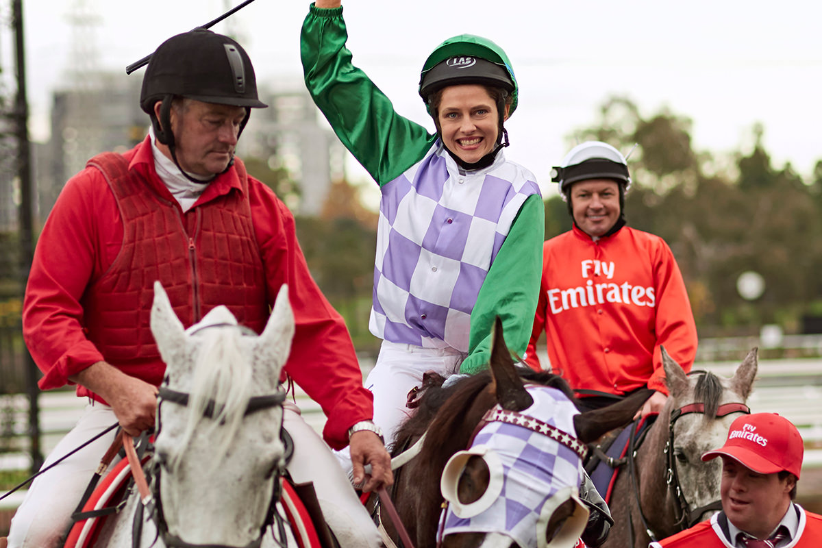 Teresa Palmer as Michelle Payne is sitting on a horse. One of her arms is raised in celebration.