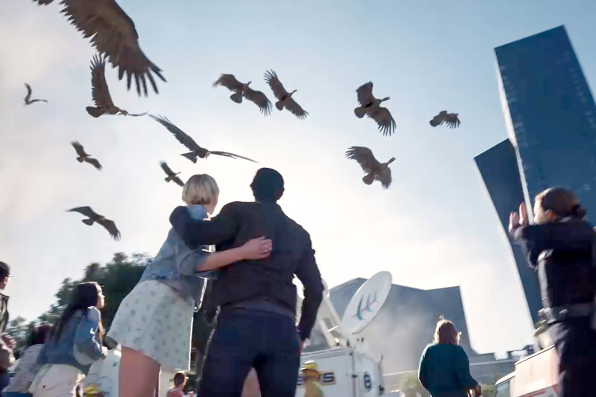 Production still from La Brea, birds fly overhead as people look up to the sky.