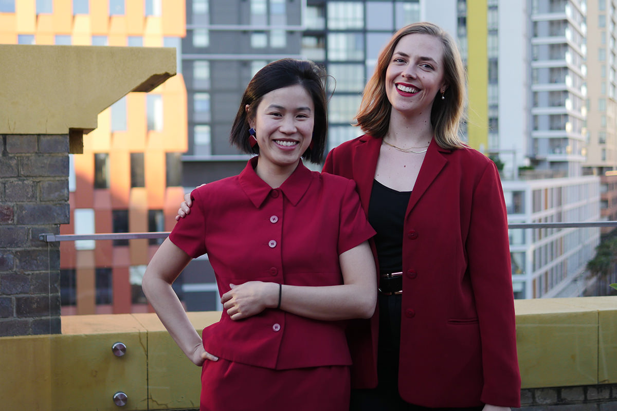The Love Bug team, Yingna Lu and Imogen McCluskey standing on a balcony